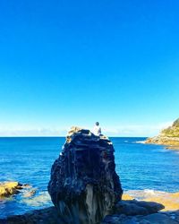 Rock formation on beach against clear blue sky