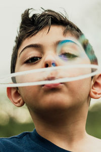 Close-up portrait of boy blowing bubbles