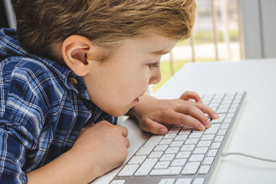 Close-up of boy using computer while sitting at home