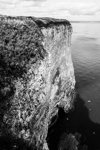 Rock formation on sea shore against sky