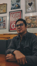 Low angle view of man looking away while sitting at table in cafe