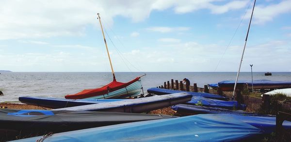 Sailboats moored on sea against sky