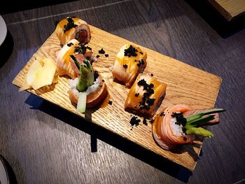 High angle view of sushi served on wooden plate at table