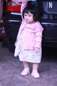 Full length of cute girl standing in car