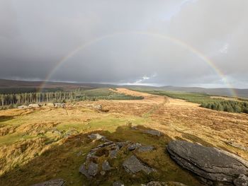 Scenic view of rainbow over landscape against sky