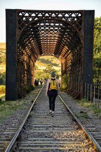 Rear view of woman walking on railroad tracks