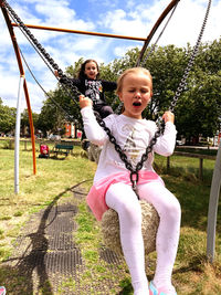 Portrait of young woman swinging at playground