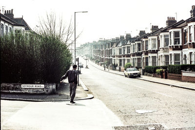 People walking on city street against sky