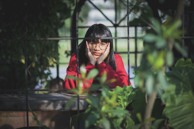 Asian teenager wearing red sweater sitting outdoor