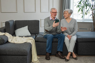 Young man using phone while sitting on sofa at home