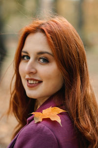 Autumn portrait of candid beautiful red-haired girl with fall leaves in hair.