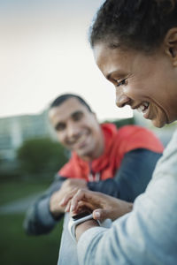 Smiling woman using smart watch while standing by friend