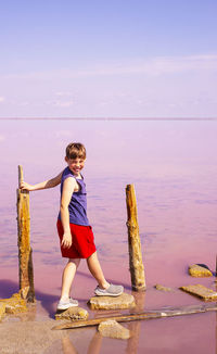 Step into the unknown with a smile and hope. a boy steps on stones on a pink fairytale lake. 