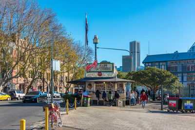 People on street by buildings in city against sky