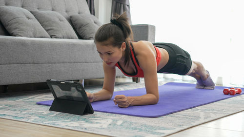 Young woman doing plank position at home