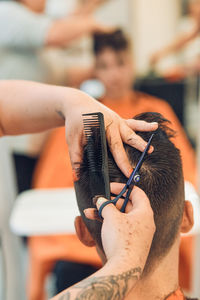 Cropped hands of barber cutting hair in salon