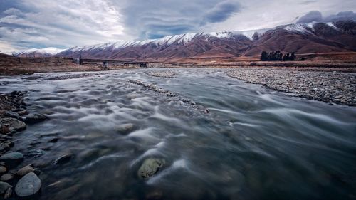 Scenic view of river by snowcapped mountains 