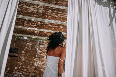 Rear view of woman looking through window