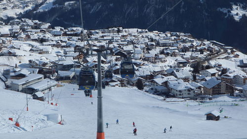 Aerial view of snow covered houses by buildings against mountains