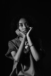 Portrait of beautiful young woman against black background