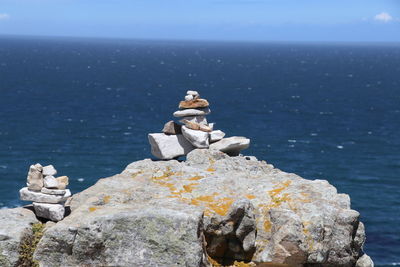 Stack of rocks by sea against sky