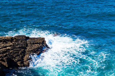 High angle view of waves splashing on rock