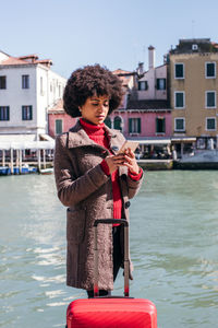 Young tourist woman checking smart mobile phone