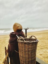 Wicker basket on beach against sky