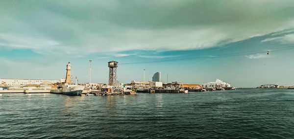 Cranes by sea against sky