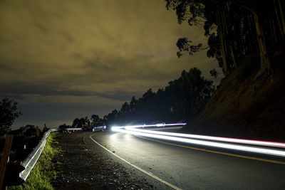 Light trails on road against sky at sunset