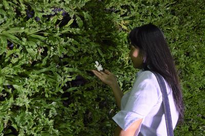 Side view of woman touching flower