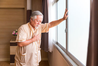 Young man looking at camera while standing on window