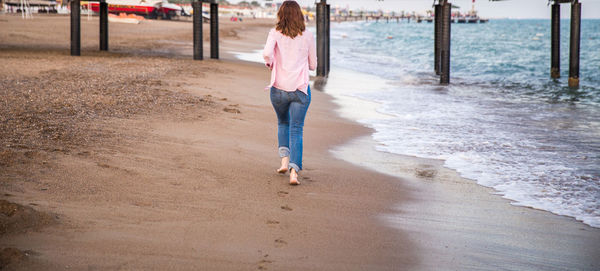 Rear view of woman running at beach