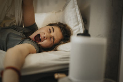 Girl yawning on bed while waking up in morning at home