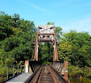 Footbridge over railroad track against sky