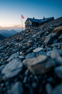 Surface level of land against house and sky during sunset