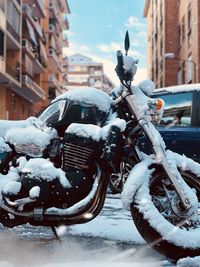 Snow covered bicycle parked on city street during winter