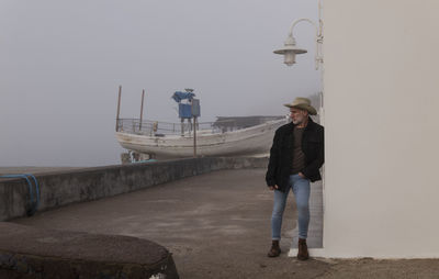 Rear view of man standing by sea against clear sky