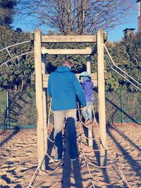 Full length of father and son climbing on ropes at playground