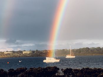 Scenic view of rainbow over sea against sky