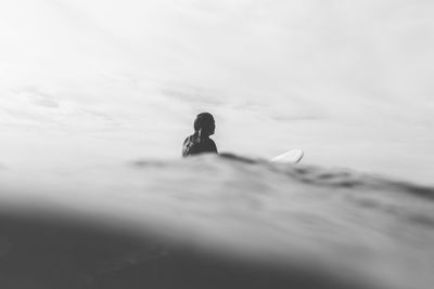 Woman with surfboard in sea against sky