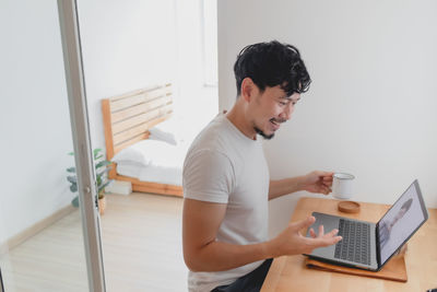 Young man using mobile phone at home