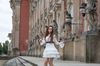 Full length of a young woman holding umbrella in city