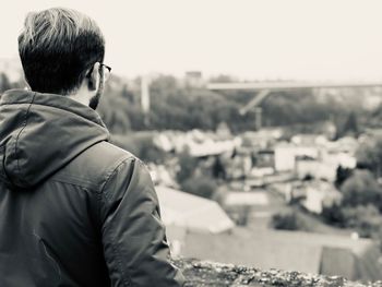 Rear view of man looking at city against sky