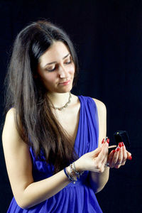 Beautiful female model in blue dress holding ring against black background