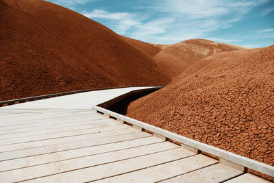 Mountains by empty boardwalk against sky