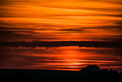 Silhouette landscape against orange sky during sunset