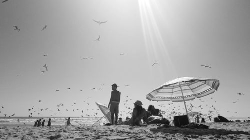 People standing on beach against clear sky