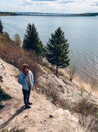 Rear view of man walking on rock by lake