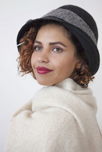 Close-up of smiling woman wearing hat against white background